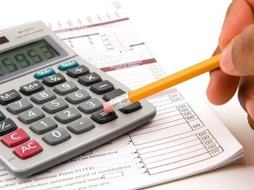 A man doing his taxes using a calculator and pencil on a white background economizar