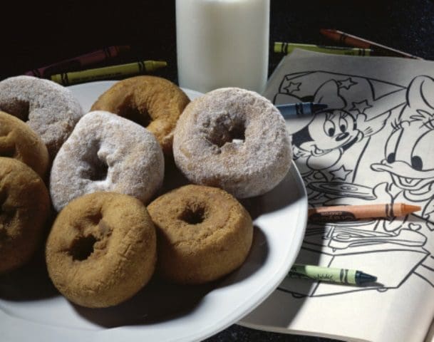 Close-up doughnuts on a plate over a coloring book
