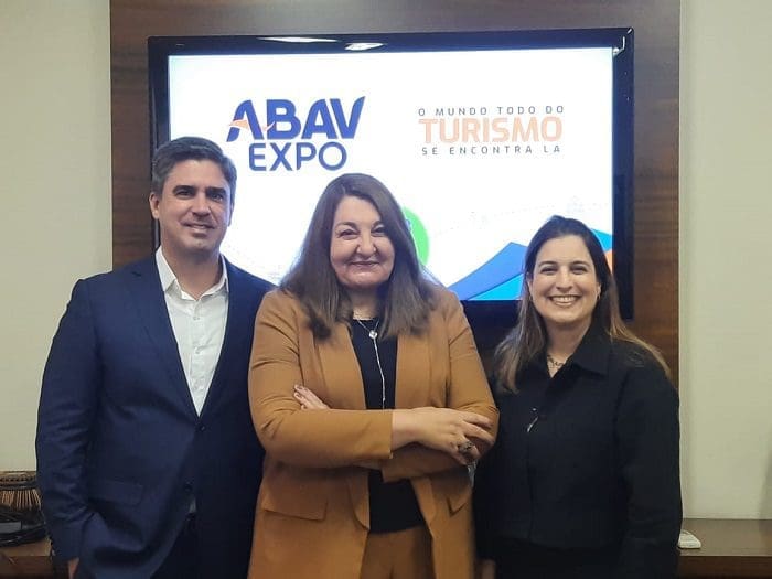 autoridades_da_abav_nacional_e_pernambuco_falam_das_expectativas_para_a_abav_expo Antonio Neves Baptista, da Empetur; Magda Nassar, presidente da ABAV Nacional; e Milu Megale, da SETUR-PE, em frente à apresentação da ABAV Expo 2022, na televisão.
