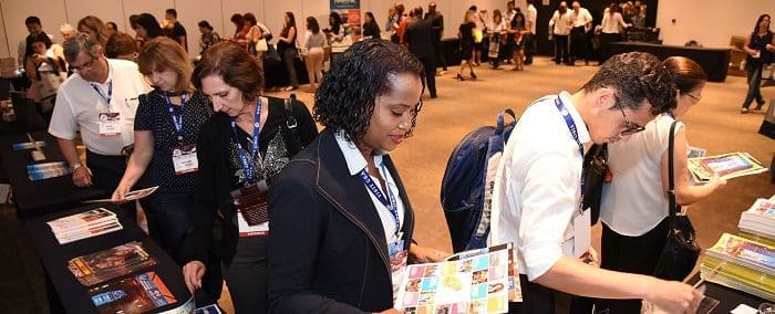Agentes de viagem e operadores de turismo olhando e segurando folders de destinos norte-americanos no Visit USA.