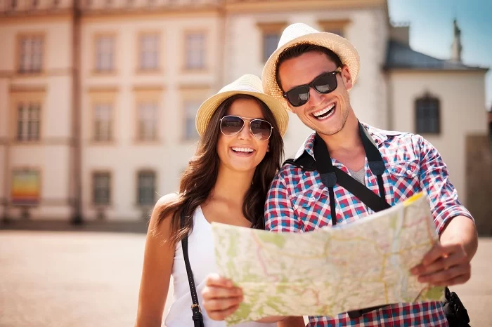 Casal de turistas com mapa nas mãos e sorrindo. Pesquisa revelou que 77% dos entrevistados do Brasil preferem destinos turísticos brasileiros, e Marcos Dias, CEO da RDC Viagens, falou sobre a vantagem de uma assinatura de viagens.
