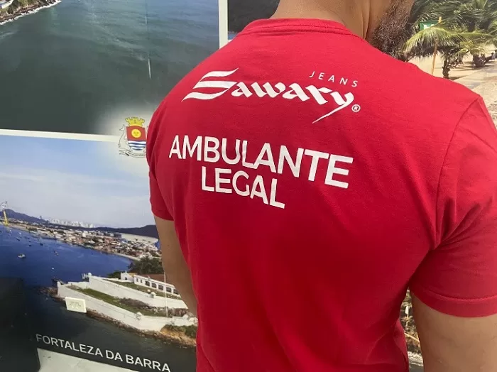 Costas da camiseta vermelha, escrito "Ambulante Legal" em branco, que os ambulantes da Praia da Enseada, no Guarujá, receberam