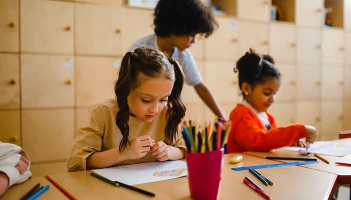 Instituto GOL lança edital: imagem de crianças sentadas à mesa, desenhando e aprendendo